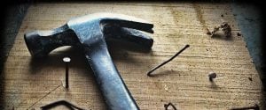 Hammer with nails on a rough hewn wooden board